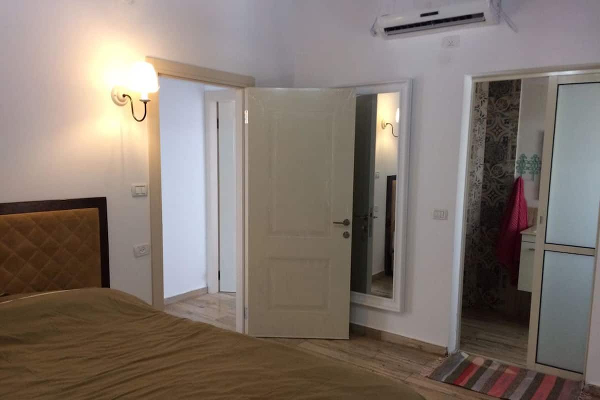 A bedroom with a bed, a door leading to a bathroom, and a wardrobe.