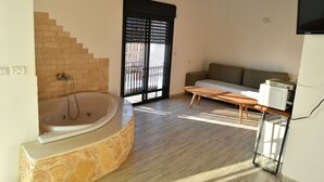 A modern bathroom with a stone sink, a bathtub, and a window with blinds. - Shlomo Cabins Boutique (Merom HaGalil)