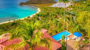 Un resort tropical con piscina, palmeras y una playa.