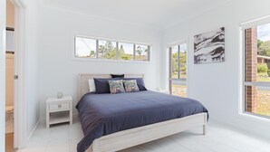 A bedroom with a bed, a nightstand, a window, and a door.
