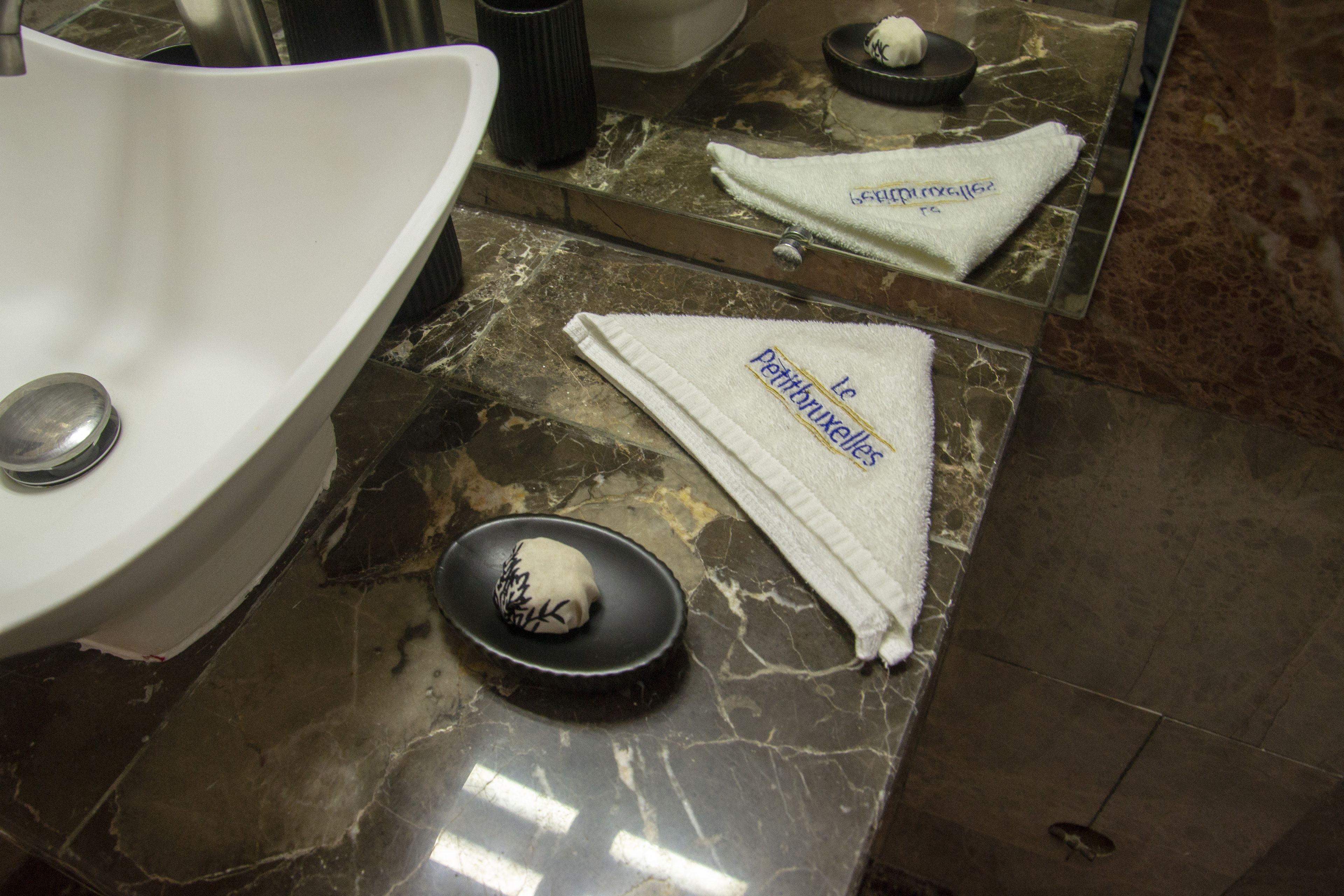 A bathroom with a white sink, a black basin, and two white towels with text on them.