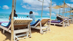 Una playa con sillones de madera y una estructura tipo sombrilla.