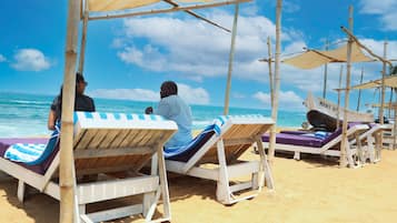 Een privéstrand, wit zand, ligstoelen aan het strand, parasols