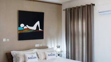 Hotelkamer met een houten bed, wit beddengoed, een kroonluchter, een schilderij en een raam met gordijnen.