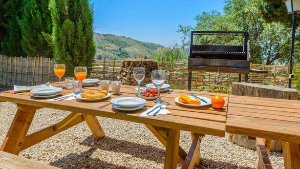 Ein Holzkreuztisch im Freien mit einem Grill, Speisen und Getränken.