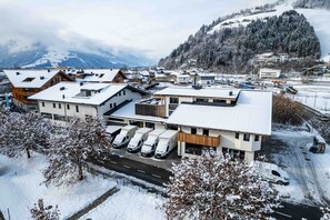 A snow-covered town with modern buildings, a parking area, and a mountainous backdrop. - Tevini Alpine Apartments - Schmittenblick, balcony (Zell am See)