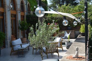 Un espacio al aire libre con mobiliario exterior, pérgola y una estatua de Buda.