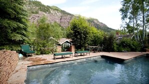Une piscine avec des chaises longues et une petite maison située dans une région montagneuse.