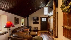 A cozy living room with leather sofas, a fireplace, a television, and a wooden floor. - Beautiful Newly Remodeled Log Cabin at Tiny Timbers Resort! (South Fork)