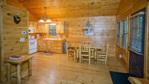 L’intérieur d’un chalet en bois comprend une cuisine, un coin repas et une porte dotée d’une fenêtre.