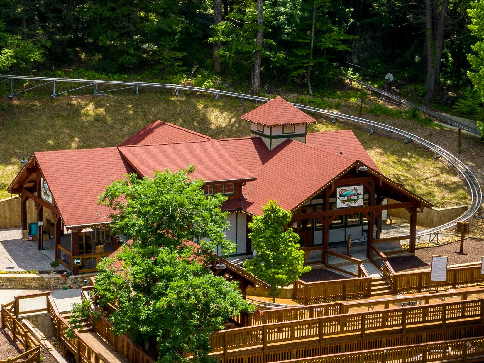 A lodge with a red roof, a small tower, and a wooden deck area.