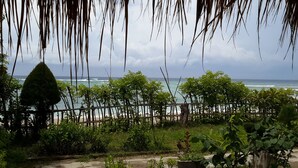 A view of a beach with a wooden fence and lush greenery in the foreground. - Hotel Gili Air & Restaurant (Gili Air)