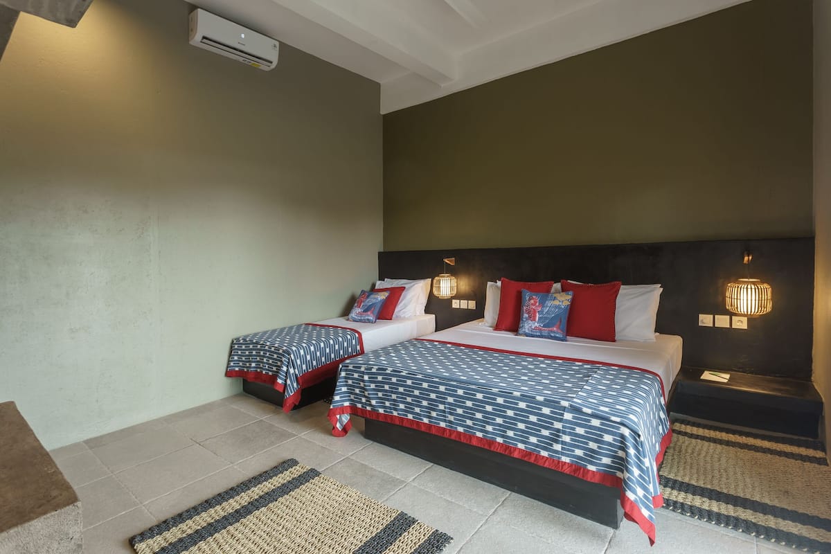 A hotel room with two beds, a large window, and a wall-mounted air conditioner.