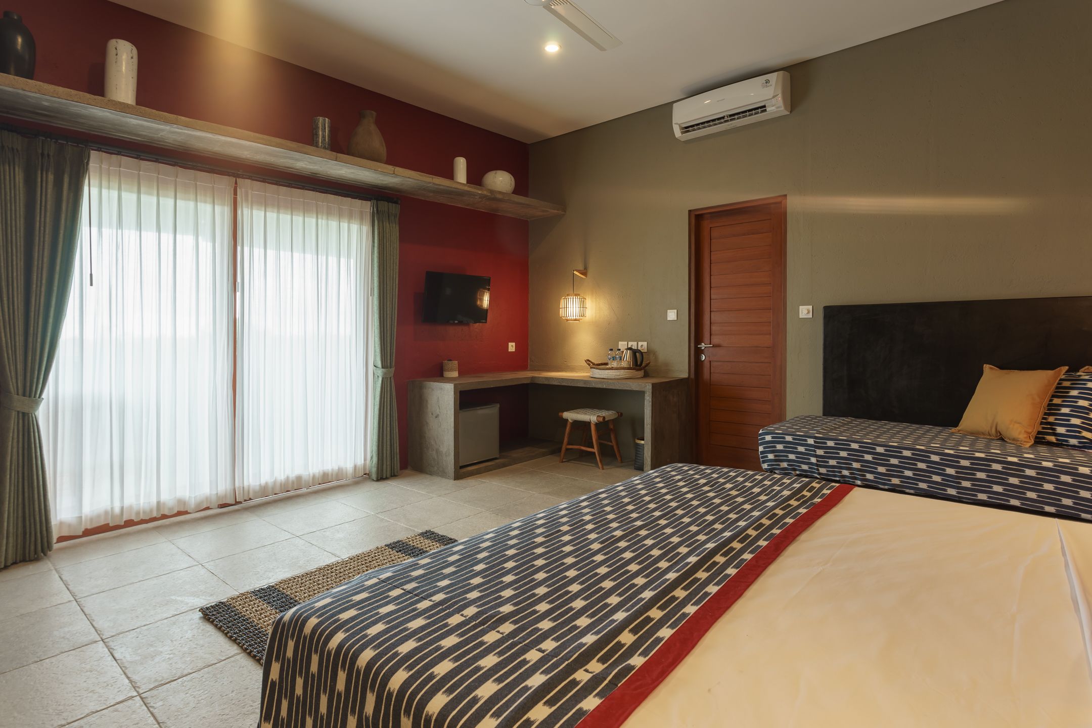 Una habitación de hotel con cama, escritorio, silla, televisor y puerta.