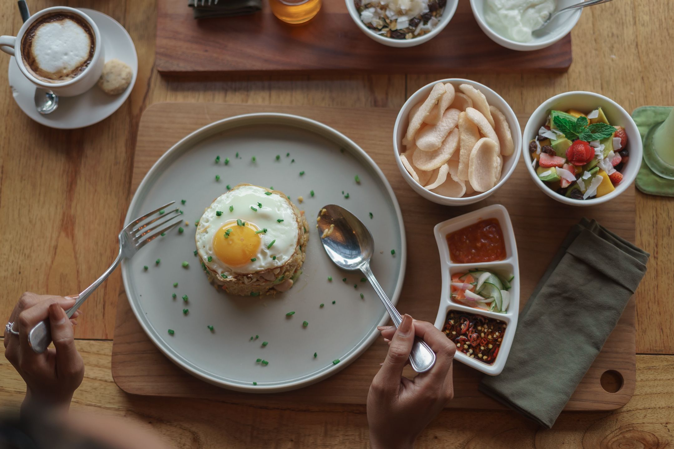 Une table mise pour le petit-déjeuner, avec une assiette de nourriture, une tasse de café et divers condiments.