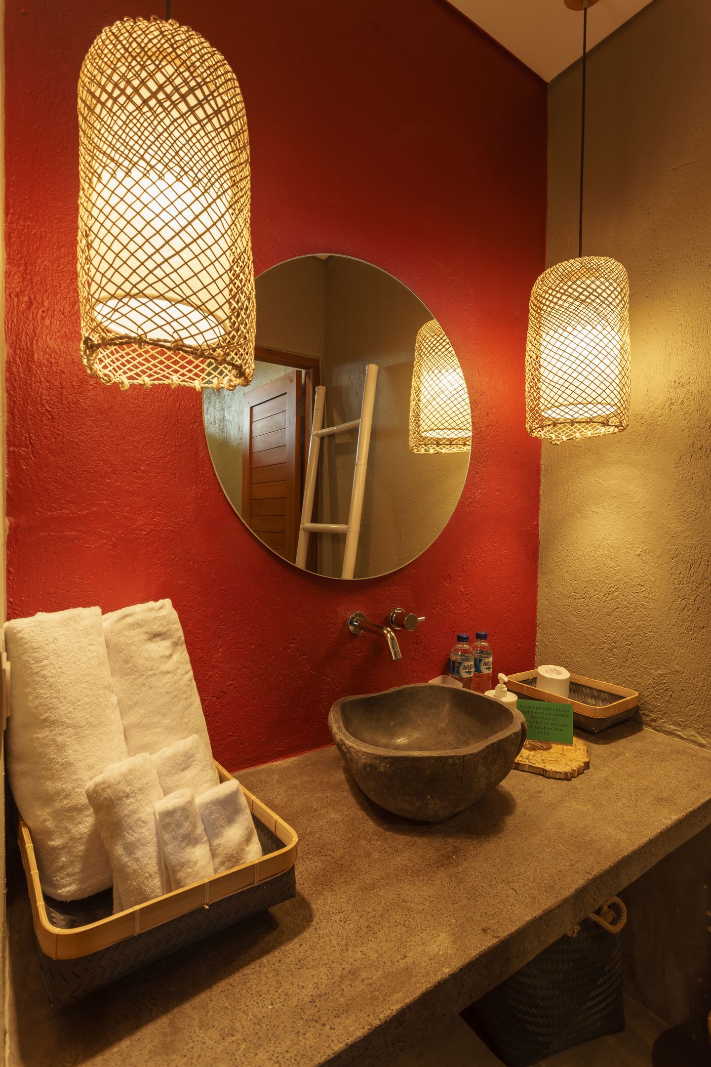 A bathroom with a round mirror, a sink, and two hanging lights.