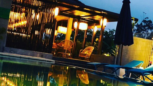 Un área de piscina con sillones de descanso y una zona de estar cubierta con sillas.