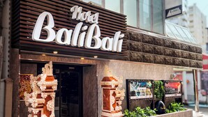 Een hotel genaamd 'Hotel Baliat' met een moderne gevel, grote ramen en een opvallende entree.