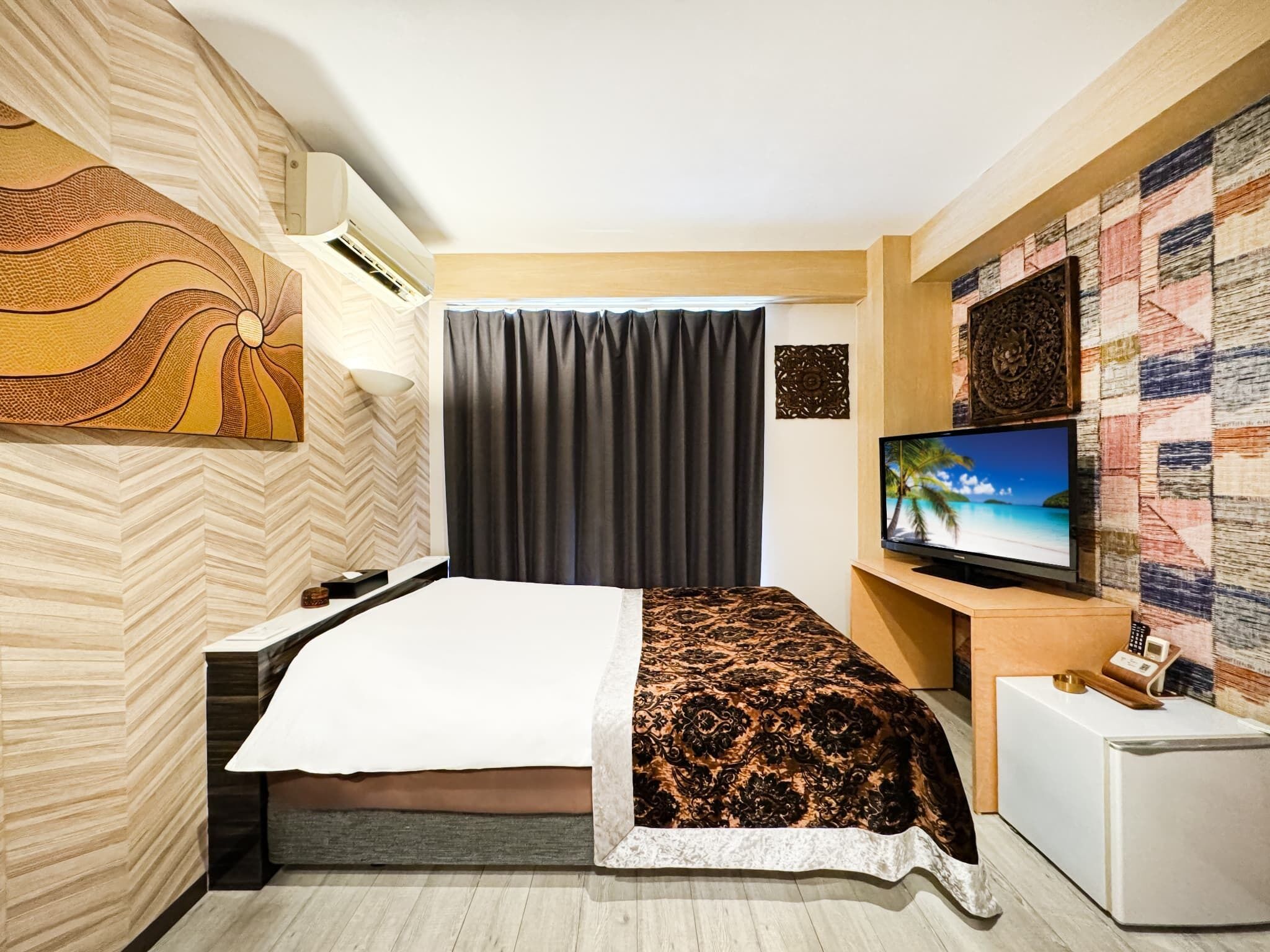 A modern hotel room with a bed, a TV, a desk, and a wall-mounted air conditioner.