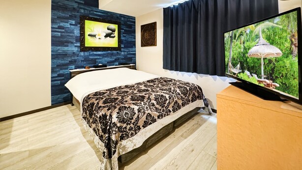 Een moderne hotelkamer met een bed, een flatscreen televisie, een aan de muur bevestigde televisie en een groot raam met gordijnen.
