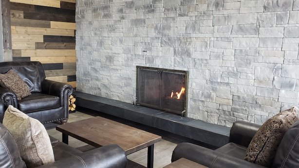 Un salon moderne avec une cheminée en pierre, des canapés en cuir et une table basse en bois.