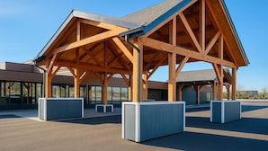 Un espace extérieur abrité, doté d’une structure en bois, de grands jardinières et offrant une vue sur un ciel dégagé.