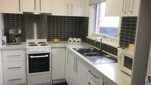 A modern kitchen with white cabinets, a stainless steel range, a built-in oven, a double sink, and a window. - Beachdoc, 300 m to the beach (St. Leonards)
