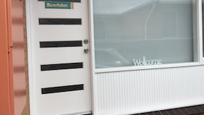 A white door with a 'Beachdoc' sign and a 'Welcome' sign on a window. - Beachdoc, 300 m to the beach (St. Leonards)