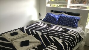 A neatly made bed with a striped bedspread, two folded blankets, and a headboard with patterned pillows. - Beachdoc, 300 m to the beach (St. Leonards)