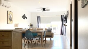 Une cuisine moderne avec un coin repas, comprenant un îlot central, un ventilateur de plafond et une vue sur la salle à manger.