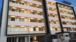 Un hôtel à plusieurs étages, doté d’un design moderne, avec des balcons à chaque niveau et une structure verticale centrale.