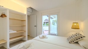 Una habitación de hotel con cama, armario, balcón y una lámpara colgante.