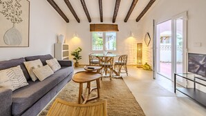 Una sala de estar con un sofá, una mesa de comedor con sillas, un televisor y un ventanal grande.