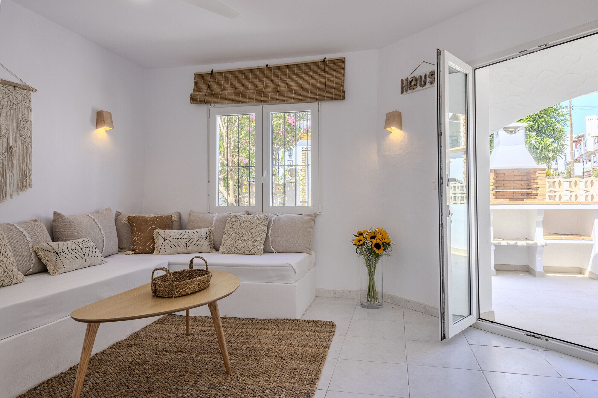 A cozy room with a white sofa, a small wooden table, and a large window with a view of the outside.