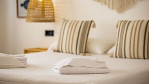 A neatly made bed with folded white towels, striped pillows, and a hanging light fixture. - Villa LA LUNA 1ª Línea Playa (Denia)