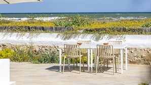 An outdoor dining area with a view of the sea, stone flooring, and white chairs. - Villa LA LUNA 1ª Línea Playa (Denia)
