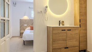 A modern bathroom with a wooden vanity, a round mirror, and a shower.