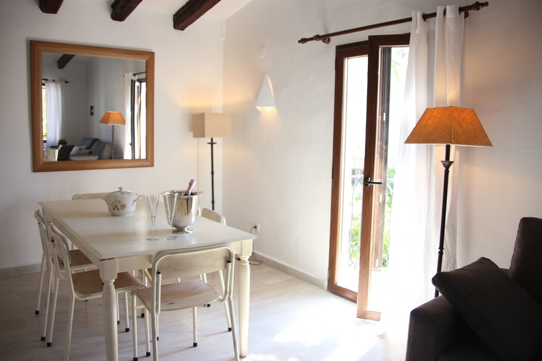 A dining area with a table, chairs, a mirror, and two lamps.