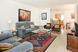 Un salon comprenant un canapé, des fauteuils, une table basse et un tapis.