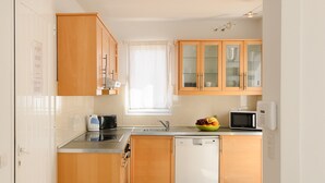 Uma cozinha moderna com armários de madeira, máquina de lavar louça, micro-ondas e uma fruteira no balcão.