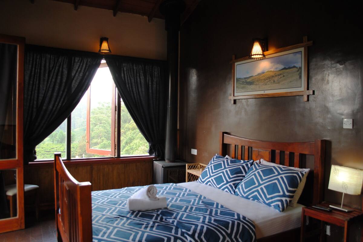 Ein Schlafzimmer mit einem hölzernen Bett, einem Nachttisch, einer Lampe, einem Fenster mit Vorhängen und einem an der Wand hängenden Bild.