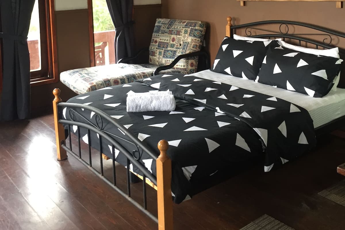 Ein Schlafzimmer mit einem Bett, einem Sessel, einem Gemälde und einem Fenster.