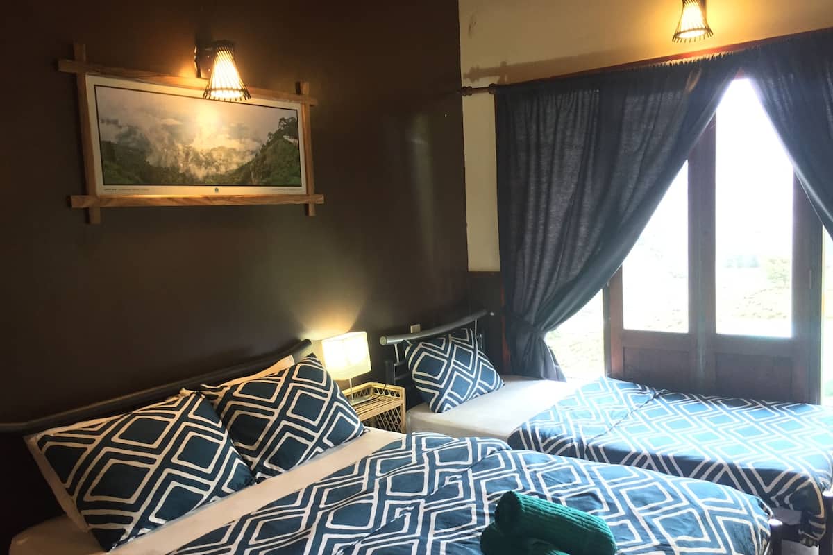Ein Hotelzimmer mit zwei Betten, beide mit gemusterten Bettdecken, einem Bild an der Wand und einem Fenster mit Vorhängen.