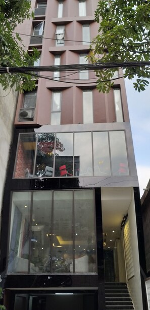A modern building with large windows, a staircase, and a tree in the foreground. - Max Boutique Hotel (Thuc Phan)