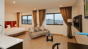 Quarto de hotel com cama, sofá e uma mesinha com garrafa e copo.