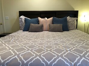 Una cama bien hecha con un edredón estampado y varias almohadas.