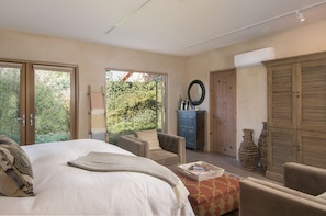 Relax in a serene space with a large bed, comfortable armchair, and air conditioning.