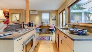 A modern kitchen with a central island, wooden cabinets, and a large window providing natural light.