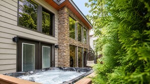 A spa area with a hot tub, stone pillar, and a wooden deck. - Gatlinburg Cottage – Hot Tub, Walk Downtown (Gatlinburg)