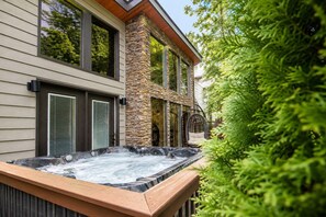 Ein Wellnessbereich mit Whirlpool, Säule aus Stein und Holzterrasse.
